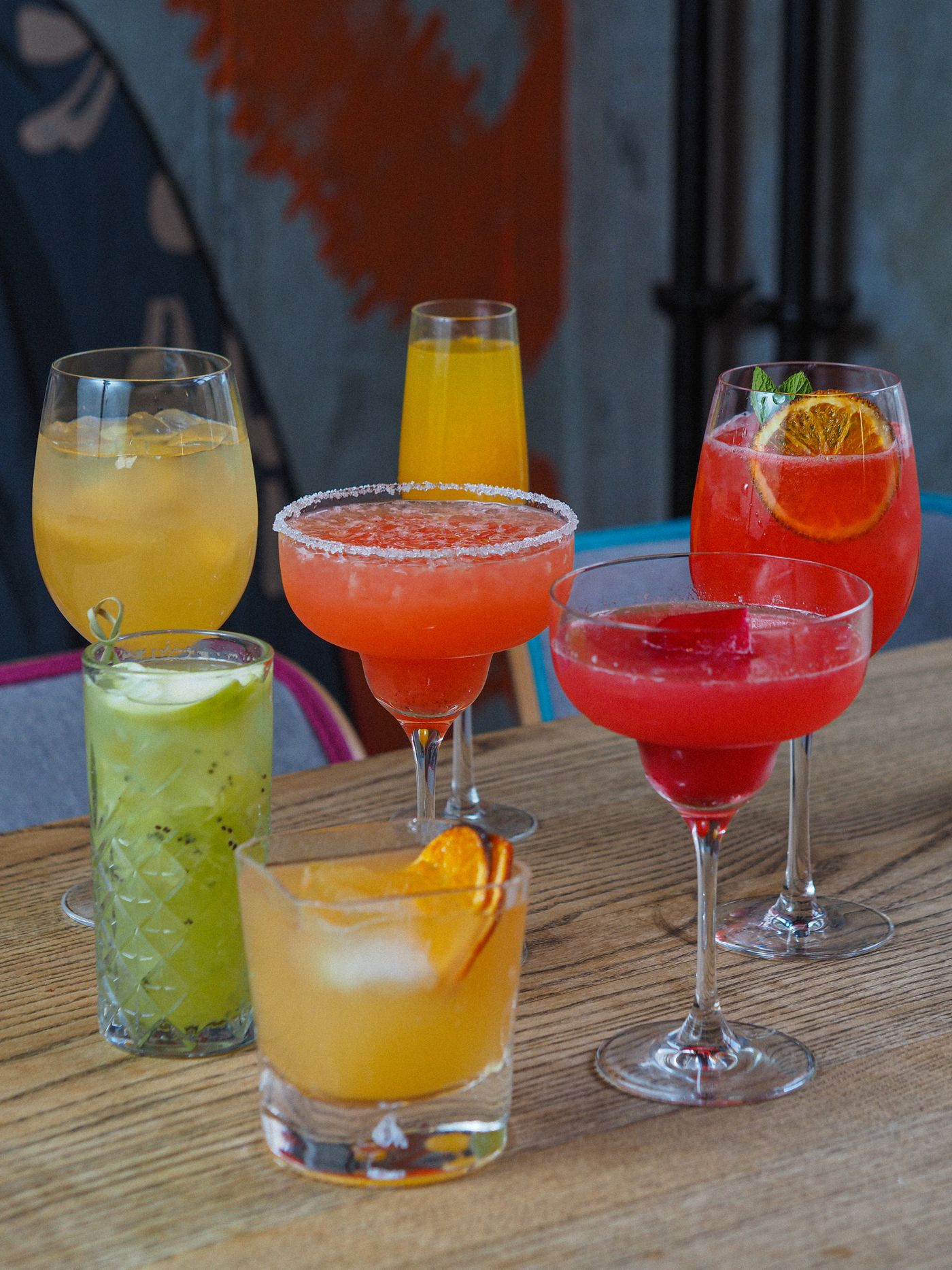 Cocktails colorés posés sur une table en bois (photo d’illustration)