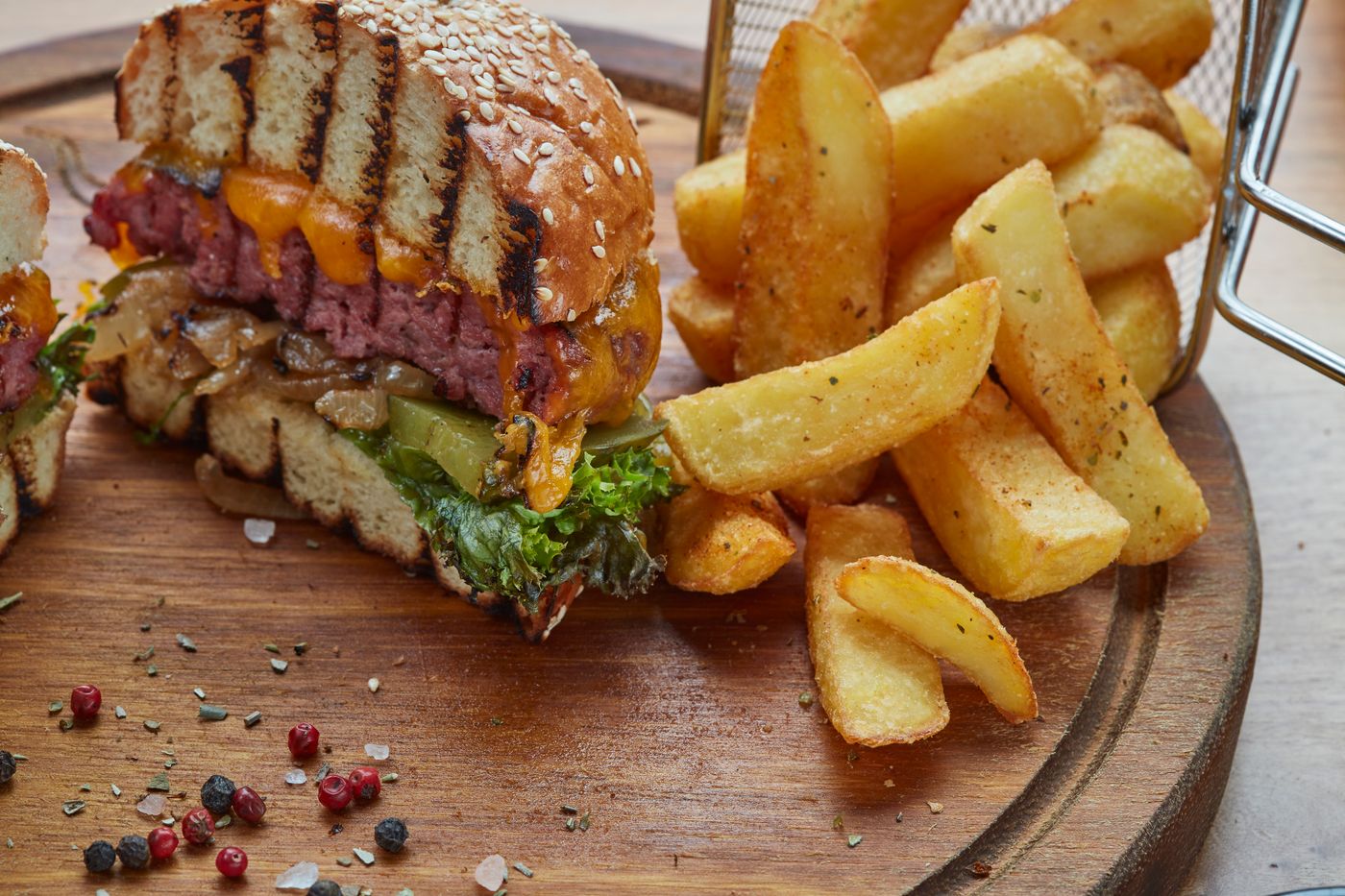 Burger généreux et frites rustiques sur une planche en bois (photo d’illustration)