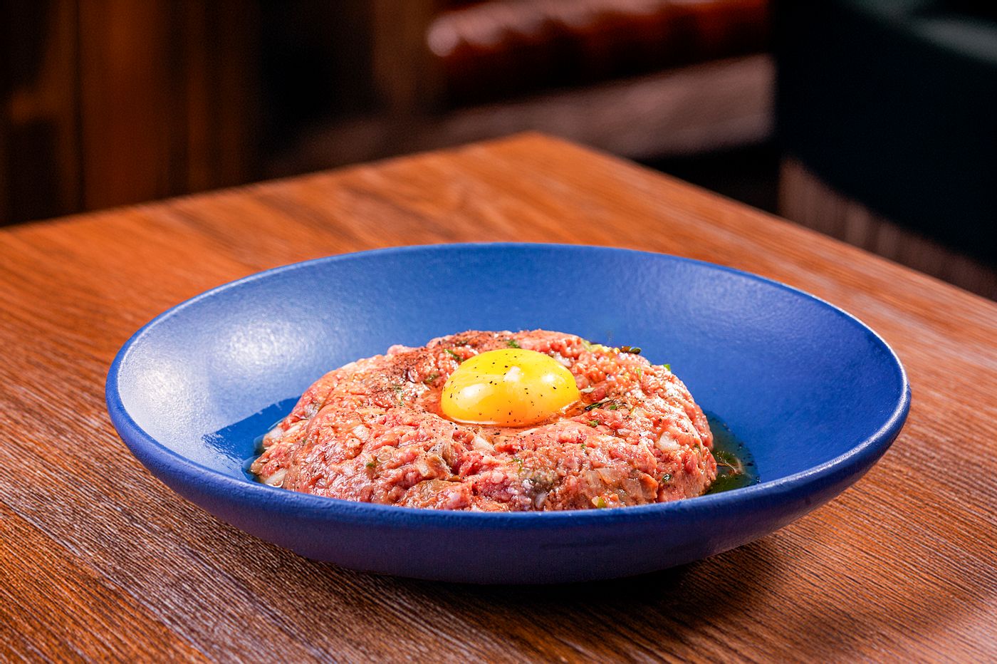Tartare de bœuf et son jaune d’œuf dans une assiette creuse bleue (photo d’illustration)