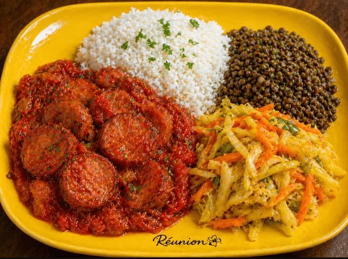 Rougail saucisse avec riz, grains et salade, dans une assiette jaune